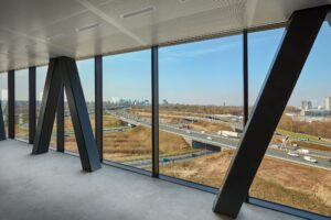 Uitzicht vanuit een modern kantoorgebouw aan de Joan Muyskenweg op snelwegen en de skyline van Amsterdam.